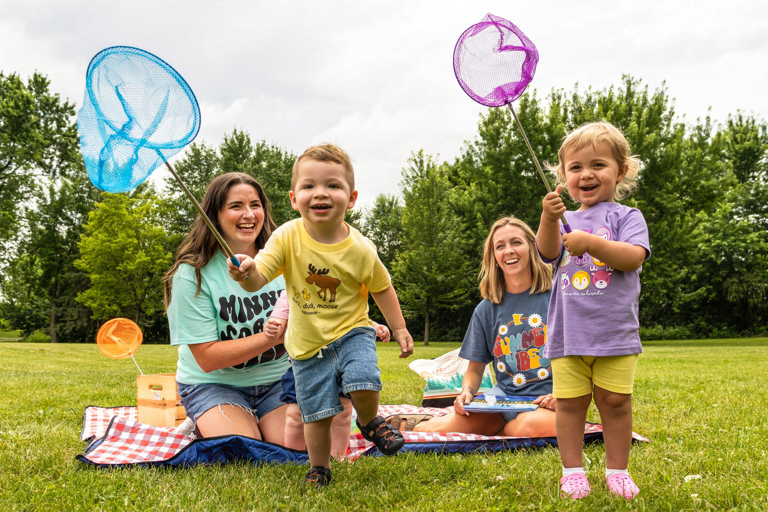Two women and two children playing with butterfly nets in a park