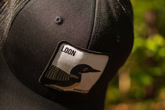 A black baseball cap with a patch that reads "Loon" with a common loon on it