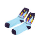 A pair of light blue crew socks with dark purple cuffs, heels, and toes, featuring a colorful Chicago skyline graphic with the word 'CHICAGO'. The graphic includes yellow and purple skyscrapers, a yellow crescent moon, and small yellow stars.
