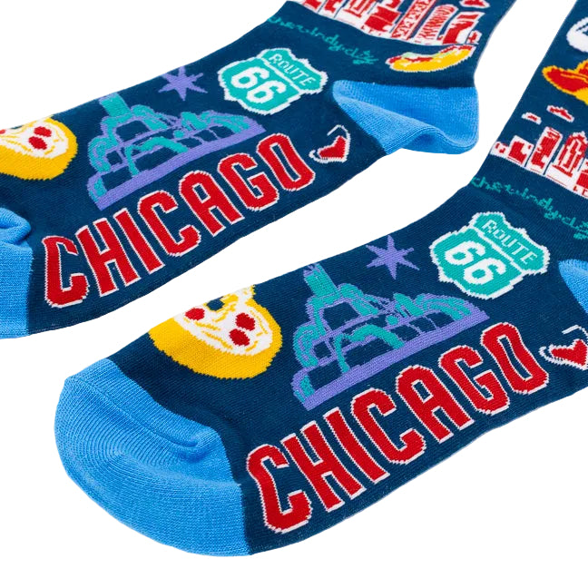 A pair of dark navy blue crew socks with a colorful Chicago-themed graphic print, featuring the word 'CHICAGO' in red, 'ROUTE 66' shields, a yellow pizza slice, and a teal water fountain, shown on a white background.