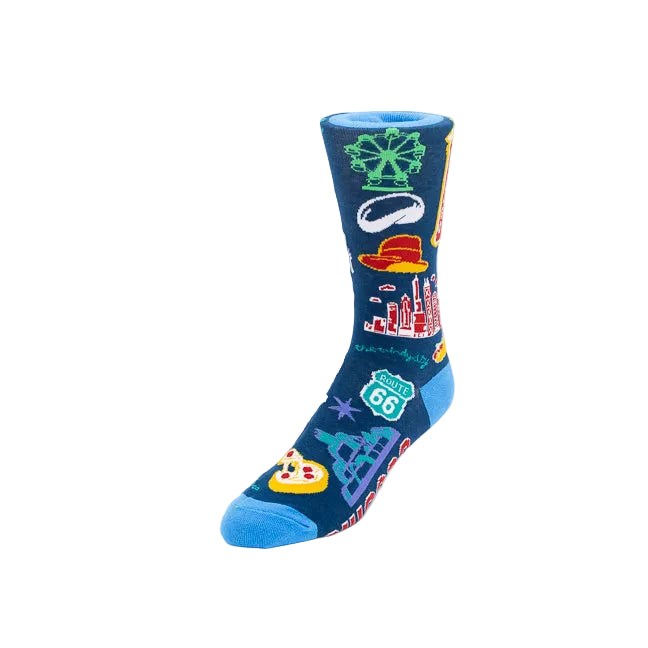 A single crew sock on a plain white background, featuring a dark blue base with colorful travel-themed graphics including a green snowflake, a red hat, a city skyline, a Route 66 shield, and a pizza slice.