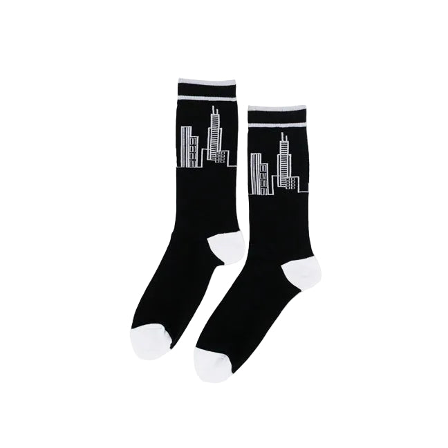 A pair of black crew socks with white toe caps, white heel accents, and a white line-art city skyline graphic on the upper leg, displayed against a clean white background.