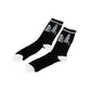 A pair of black crew socks with white toes, heels, and cuffs, featuring a white line-art skyscraper graphic on the upper leg, displayed on a clean white background.