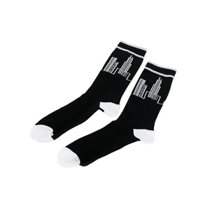 A pair of black crew socks with white toes, heels, and cuffs, featuring a white line-art skyscraper graphic on the upper leg, displayed on a clean white background.
