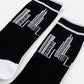 Black crew socks with white ribbed cuffs, white toes, and a white line-art graphic of skyscrapers, shown on a white background.