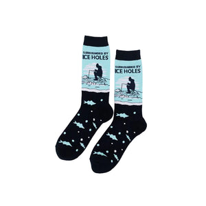 A pair of crew socks on a plain white background. The socks are dark navy with a light blue graphic on the upper calf showing a figure ice fishing with the text 'SURROUNDED BY ICE HOLES', and a lower section with light blue fish and bubbles.