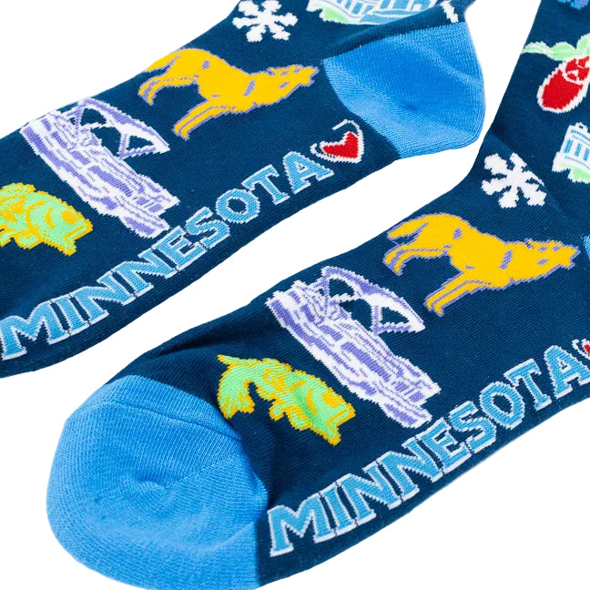 A pair of crew socks with a dark blue background featuring colorful illustrations of Minnesota landmarks, animals, and the word 'UFFDA' in yellow, with bright blue heels, toes, and cuffs.