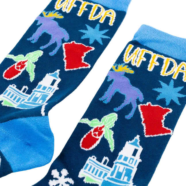 A pair of crew socks with a dark blue background featuring colorful illustrations of Minnesota landmarks, animals, and the word 'UFFDA' in yellow, with bright blue heels, toes, and cuffs.