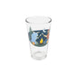 A clear glass pint glass featuring a colorful illustration of a campfire scene with Babel the Blue ox, Paul Bunyan, trees, a moon, and a campfire, set against a plain white background.