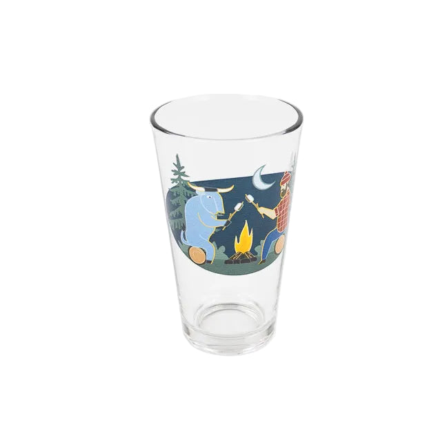 A clear glass pint glass featuring a colorful illustration of a campfire scene with Babel the Blue ox, Paul Bunyan, trees, a moon, and a campfire, set against a plain white background.