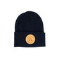 A Navy blue knit beanie hat with a folded cuff, featuring a circular tan leather patch on the front with crossed oars and the text 'GREAT UP NORTH' set against a white background.
