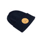 A Navy blue knit beanie hat with a folded cuff, featuring a circular tan leather patch on the front with crossed oars and the text 'GREAT UP NORTH' set against a white background.