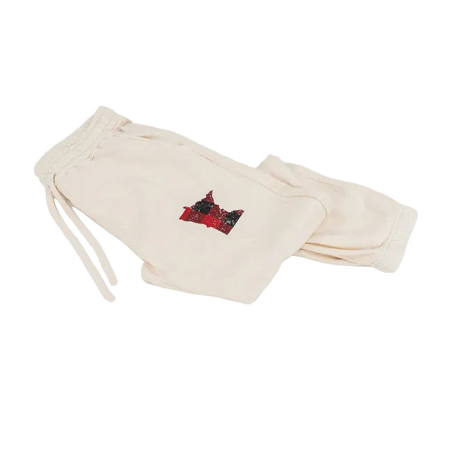 Cream-colored sweatpants with a small red and black graphic patch on the left thigh, displayed on a clean white background.