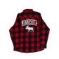 A red and black buffalo plaid flannel shirt shown from the back, featuring 'MINNESOTA' in white varsity-style letters above a white moose graphic, laid flat on a light gray background.