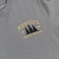 Close-up of a heather gray t-shirt featuring a distressed yellow and black graphic on the chest that reads 'MINNESOTA 1858 -NORTH COUNTRY-' with pine tree silhouettes.