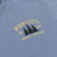 Close-up of a heathered blue t-shirt featuring a vintage-style graphic on the chest with the text 'MINNESOTA 1858 -NORTH COUNTRY-' and three black pine trees.