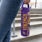 A close-up of a woman holding a purple and yellow insulated water bottle with Minnesota Vikings text and the Minnesota Vikings NFL logo.