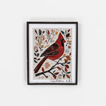 Framed artwork of a red bird on a branch with leaves and flowers on a white background