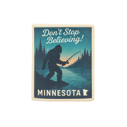 Patch with a silhouette of Bigfoot fishing, text 'Don't Stop Believing! Minnesota', and a state outline on a white background.