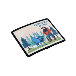 A patch featuring Paul Bunyan and Babe the Blue Ox set against a forest of pine trees. Text reads Minnesota, Est. 1858. The patch is set against a white background.