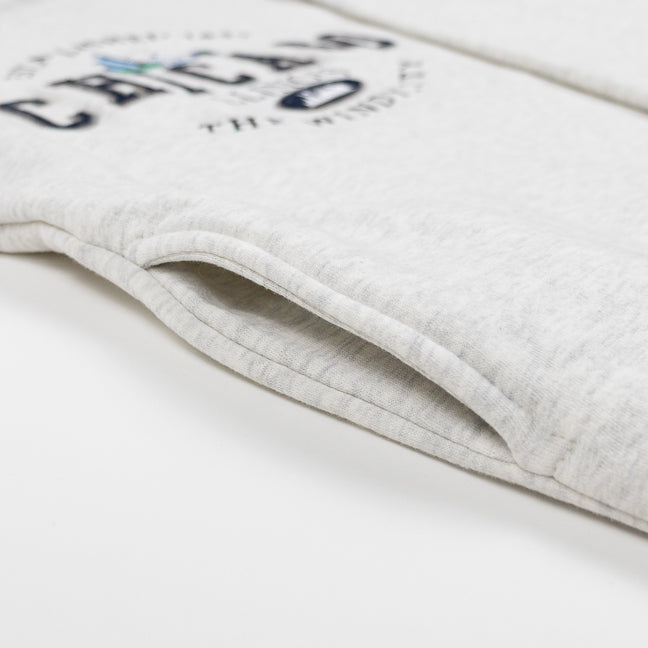 Close up of a pocket featured on a grey sweatshirt with a Chicago design.