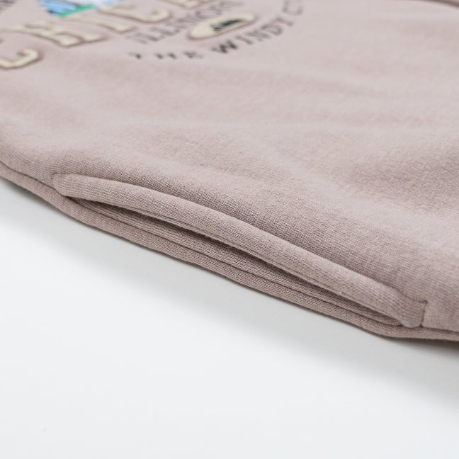 Close up of a pocket in a rose gold sweatshirt with a Chicago design.
