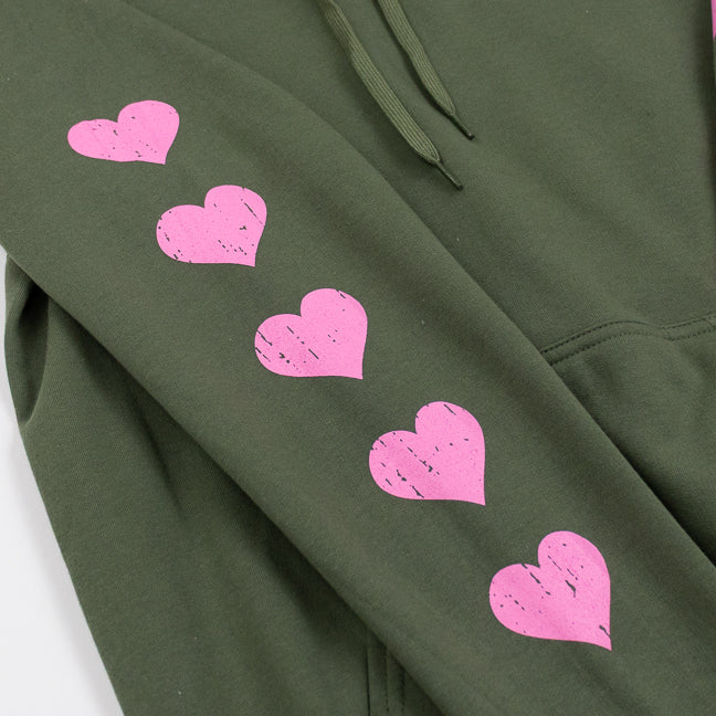 Close up of a green hoodie sweatshirt with pink hearts running down the sleeve.
