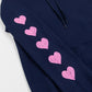 Close up of a pink hearts running down the sleeve of a navy blue sweatshirt.