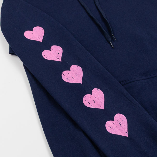 Close up of a pink hearts running down the sleeve of a navy blue sweatshirt.