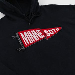 A close-up of a black hoodie featuring a red and white embroidered pennant patch on the chest with the text 'MINNE SOTD'.