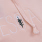 Close-up of a pink fabric with embroidered text and floral design.