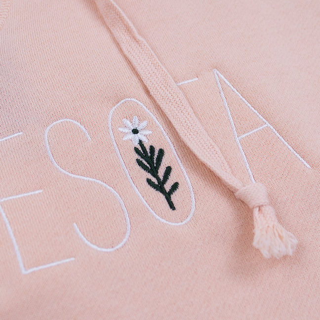 Close-up of a pink fabric with embroidered text and floral design.