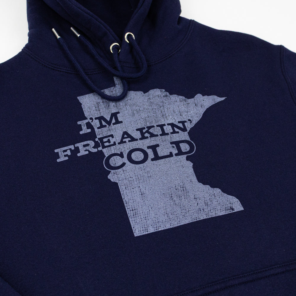 Navy hooded sweatshirt with an outline of the shape of Minnesota and text that reads "I'm Freakin' Cold."