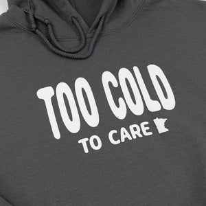 Gray hooded sweatshirt with white bubble font that reads "Too Cold to Care" across the front in white. 