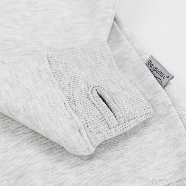 Close-up of a light gray heathered sweatshirt showing a folded cuff with a thumbhole opening and a small gray fabric tag reading 'Baypointe'.