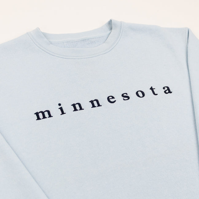 Light blue sweatshirt with 'minnesota' printed on it against a white background