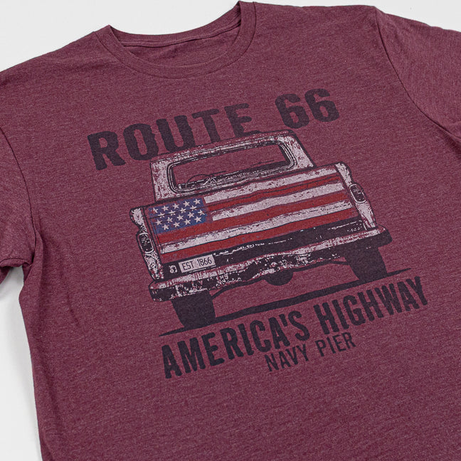 Maroon t-shirt with graphic of a truck and American flag, text 'ROUTE 66 AMERICA'S HIGHWAY NAVY PIER' on a white background.