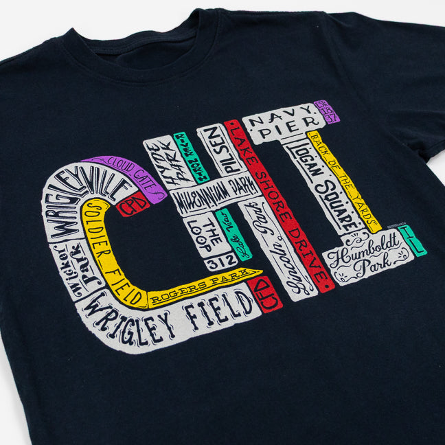 Black t-shirt with colorful text design featuring various Chicago landmarks and neighborhoods on a white background