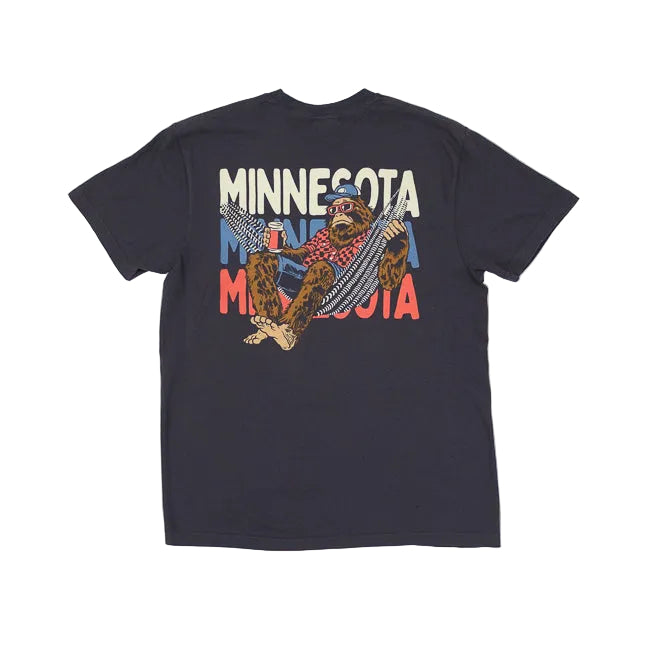 Graphite colored t-shirt with a graphic of bigfoot lying in a hammock and holding a beer on a white background