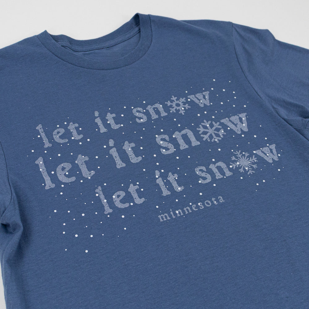 Blue t-shirt with 'let it snow' text and snowflake graphics on a light gray background