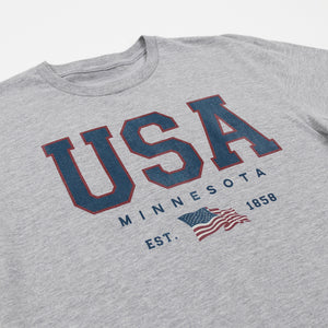 Grey tee shirt that reads USA Minnesota Est. 1858 and a USA flag on a white background.