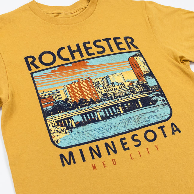 A Mustard colored t-shirt with a city scene and text "Rochester, Minnesota Med City" on a white background.
