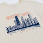 Beige t-shirt with navy blue Chicago skyline graphic and 'Windy City Chicago' text in pink.