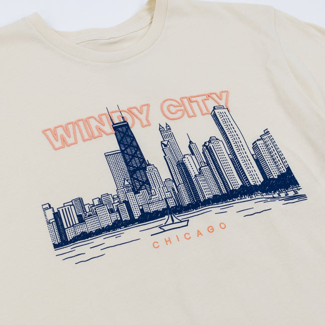 Beige t-shirt with navy blue Chicago skyline graphic and 'Windy City Chicago' text in pink.