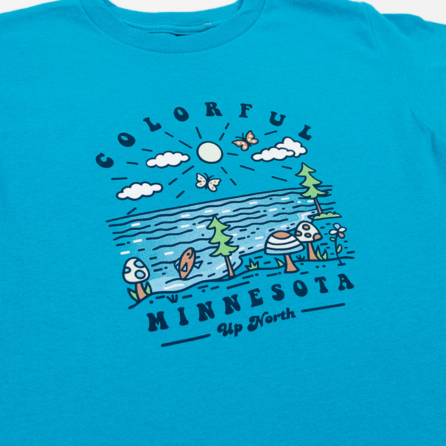Blue t-shirt with a graphic design of trees, mushrooms, and text on a white background